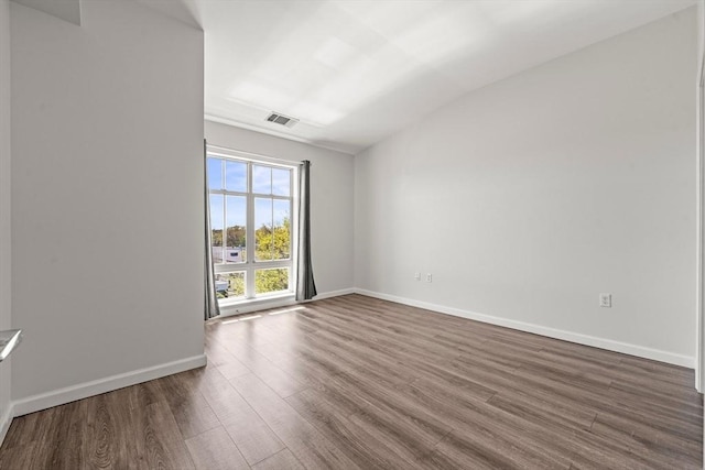 empty room with baseboards, visible vents, lofted ceiling, and dark wood-type flooring
