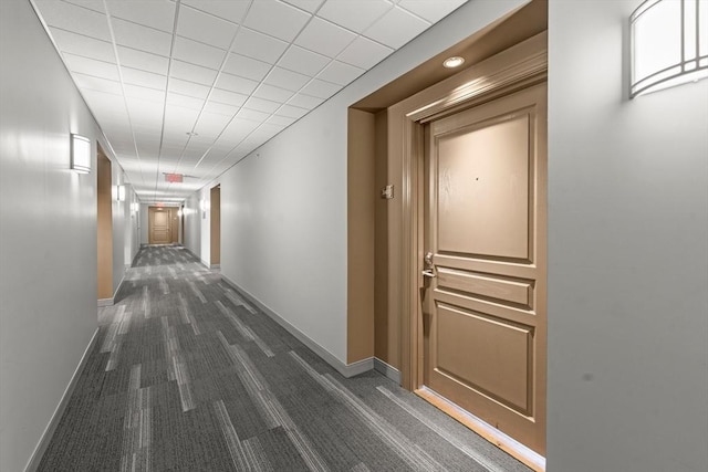 hall featuring baseboards and dark colored carpet