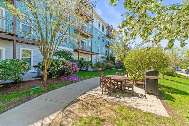 view of home's community with outdoor dining space, a yard, and a patio area