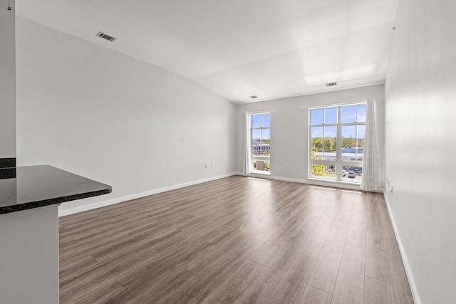 unfurnished living room featuring visible vents, baseboards, lofted ceiling, and dark wood finished floors