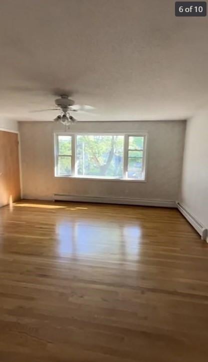 unfurnished room featuring dark hardwood / wood-style floors, a healthy amount of sunlight, and baseboard heating