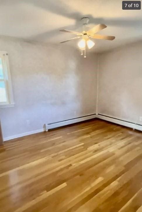 empty room featuring hardwood / wood-style flooring, a baseboard radiator, and ceiling fan