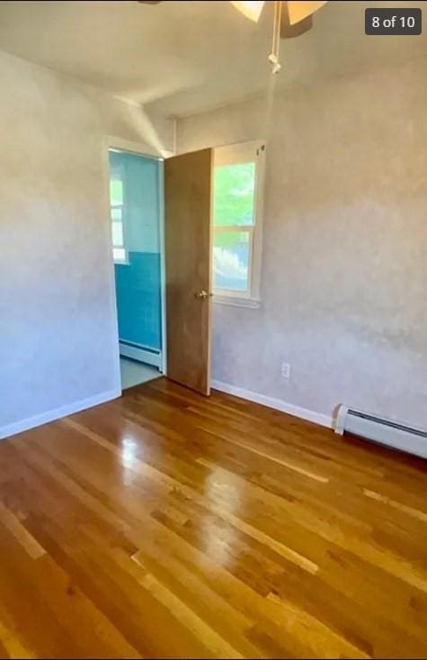 spare room featuring baseboard heating and hardwood / wood-style flooring