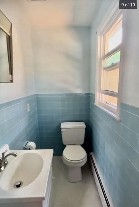 bathroom with vanity, toilet, tile walls, and a baseboard heating unit