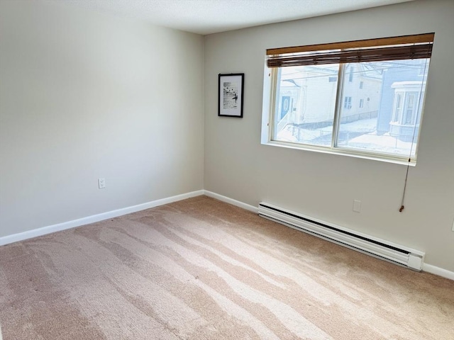 spare room featuring carpet floors, baseboard heating, and baseboards