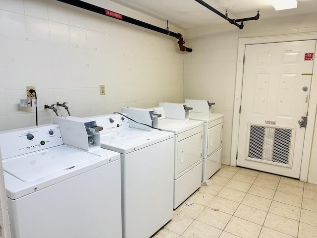 community laundry room featuring washing machine and dryer and light tile patterned flooring