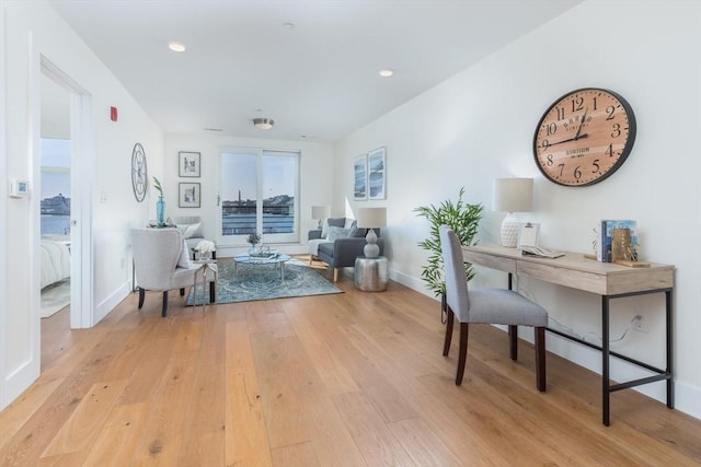 living room with recessed lighting, baseboards, and light wood-type flooring