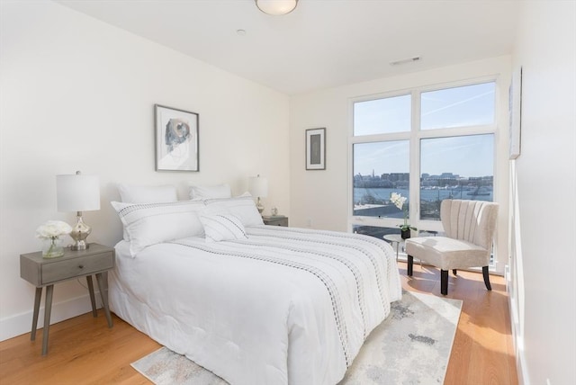 bedroom featuring a city view, baseboards, and light wood-style floors