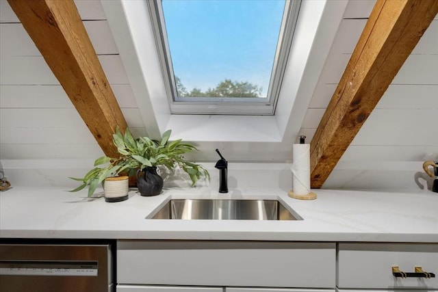66 S W Dr, Dennis, MA 02638 - kitchen view of dishwashing machine, light stone countertops, white cabinetry, and a skylight