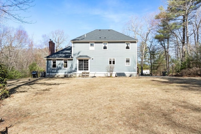 rear view of property featuring a shingled roof, a chimney, and entry steps