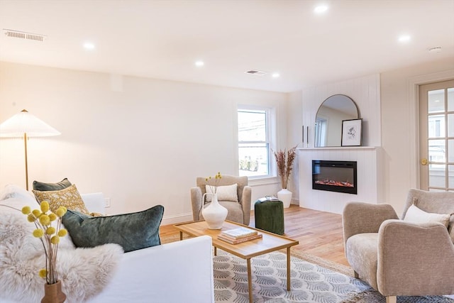 living room featuring a tiled fireplace and light hardwood / wood-style floors