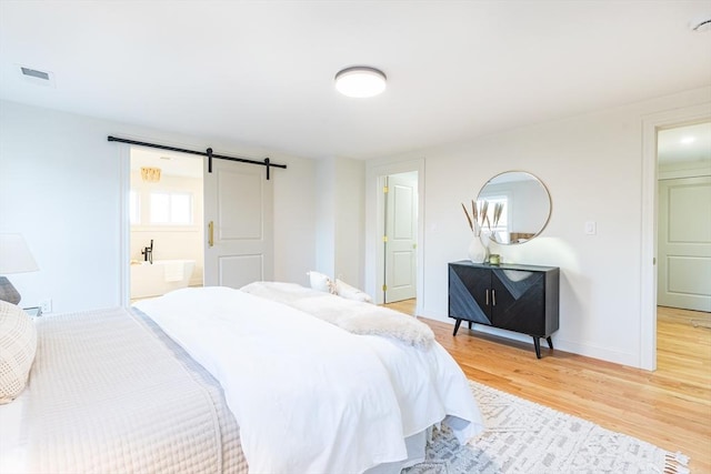 bedroom with hardwood / wood-style floors, a barn door, and ensuite bathroom