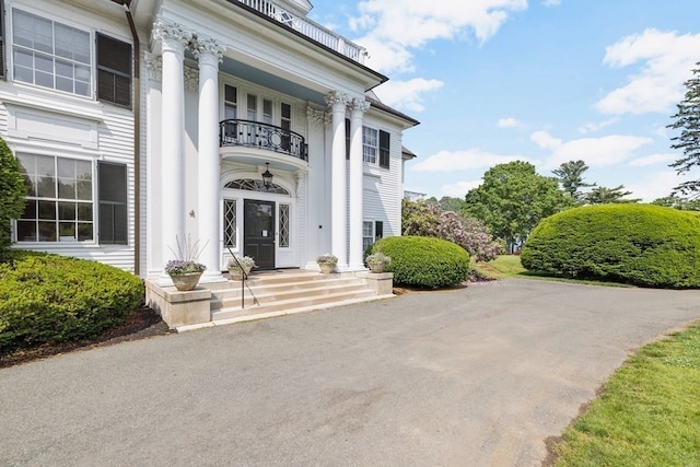 view of exterior entry featuring a balcony and french doors