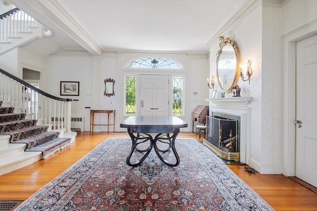 entrance foyer with radiator heating unit, light hardwood / wood-style floors, and crown molding