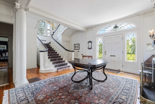 foyer with crown molding, light hardwood / wood-style floors, and decorative columns