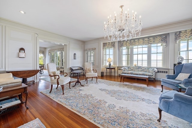 living room with plenty of natural light, a chandelier, dark wood-type flooring, and ornamental molding