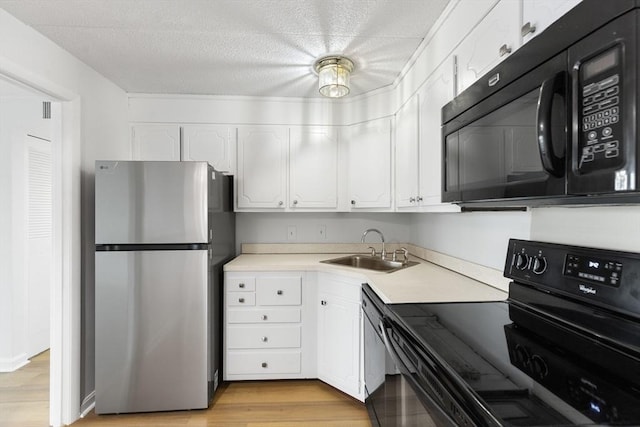 53 Melrose St Unit 7F, Melrose, MA 02176 - kitchen with black appliances, a sink, white cabinets, light countertops, and light wood-type flooring