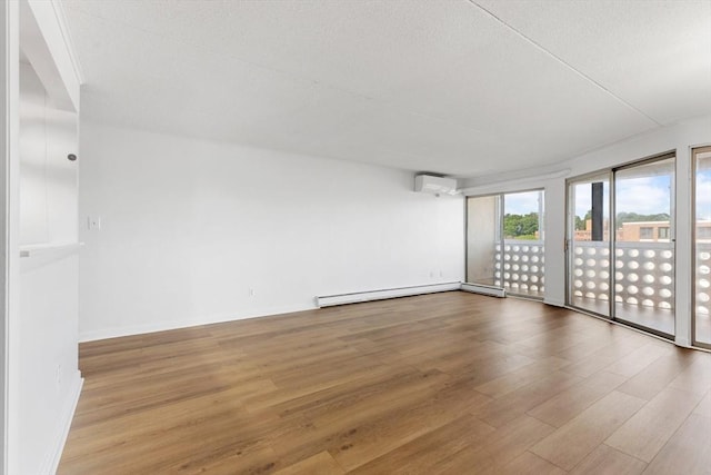 53 Melrose St Unit 7F, Melrose, MA 02176 - unfurnished room with a wall unit AC, baseboard heating, wood finished floors, a textured ceiling, and baseboards