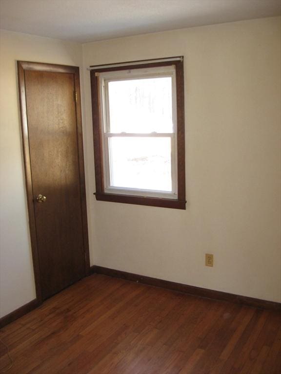 unfurnished bedroom featuring dark wood-style floors, a closet, and baseboards