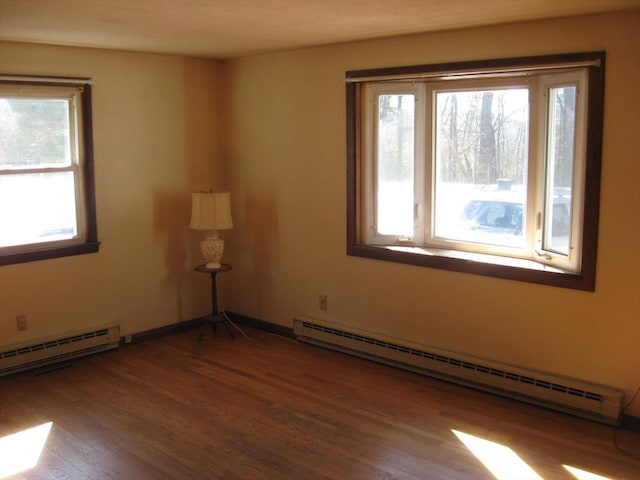 empty room featuring baseboards, baseboard heating, and wood finished floors