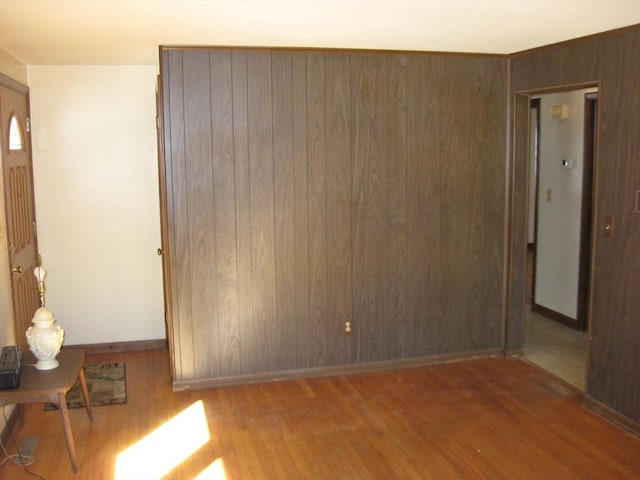 empty room with wooden walls, baseboards, and wood finished floors