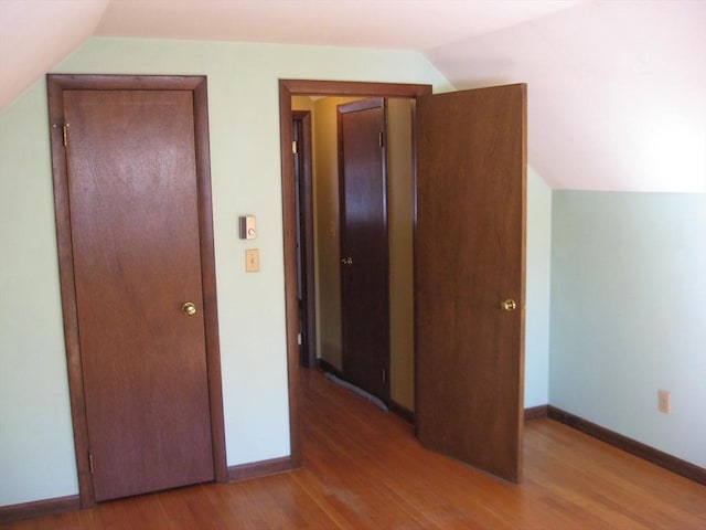 unfurnished bedroom with lofted ceiling, baseboards, and light wood finished floors