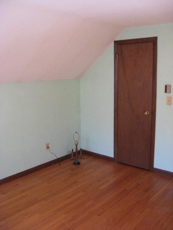 bonus room featuring lofted ceiling, light wood-type flooring, and baseboards