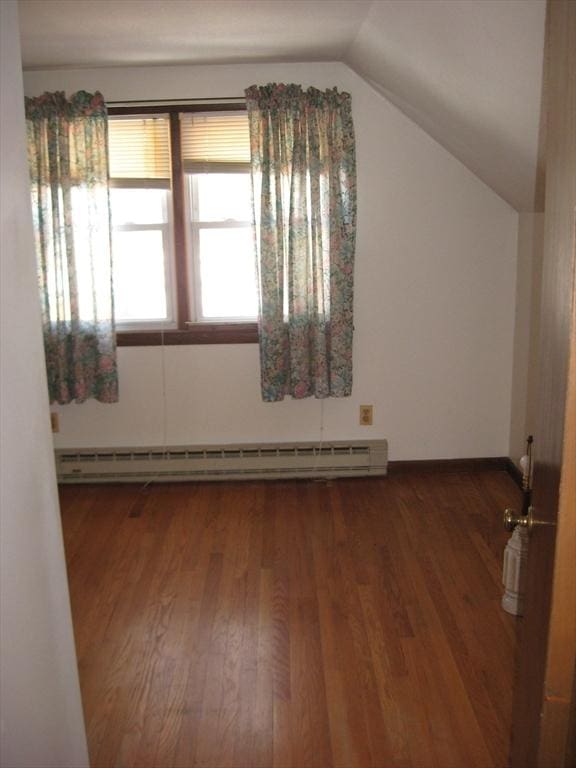 additional living space with a baseboard heating unit, wood finished floors, and lofted ceiling