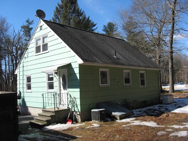 view of side of home with central air condition unit and a shingled roof