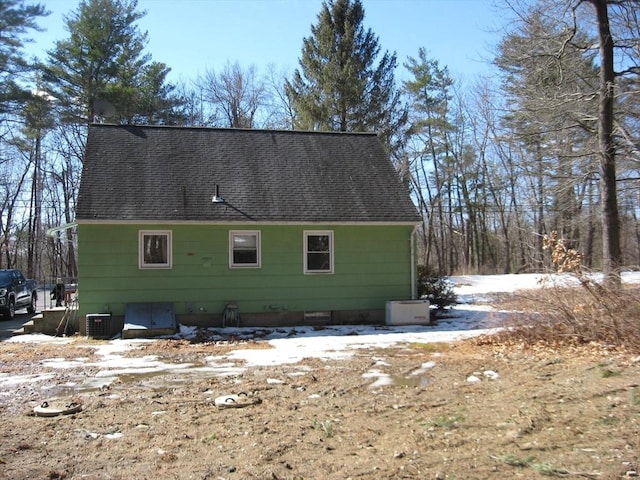 view of side of property featuring central AC and a shingled roof