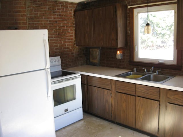 kitchen with brick wall, white appliances, a sink, light countertops, and tasteful backsplash