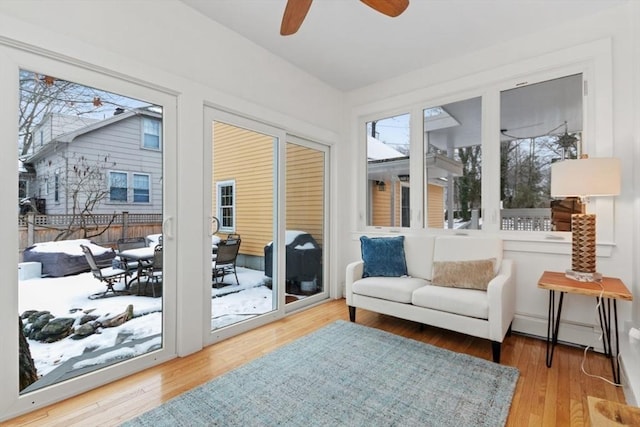 sunroom / solarium with a baseboard radiator and ceiling fan