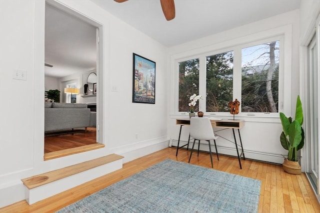 office space featuring hardwood / wood-style flooring, a baseboard heating unit, and ceiling fan