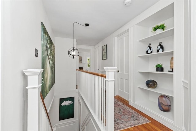 hallway with built in shelves and wood-type flooring