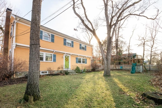 back of property with a playground and a lawn