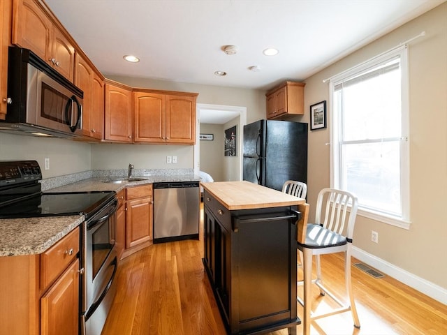 kitchen featuring a kitchen island, appliances with stainless steel finishes, sink, and light hardwood / wood-style floors