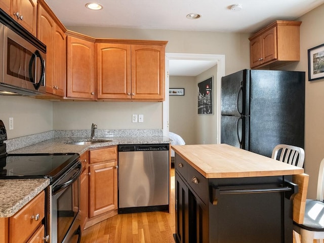 kitchen with wood counters, sink, a center island, light hardwood / wood-style flooring, and stainless steel appliances