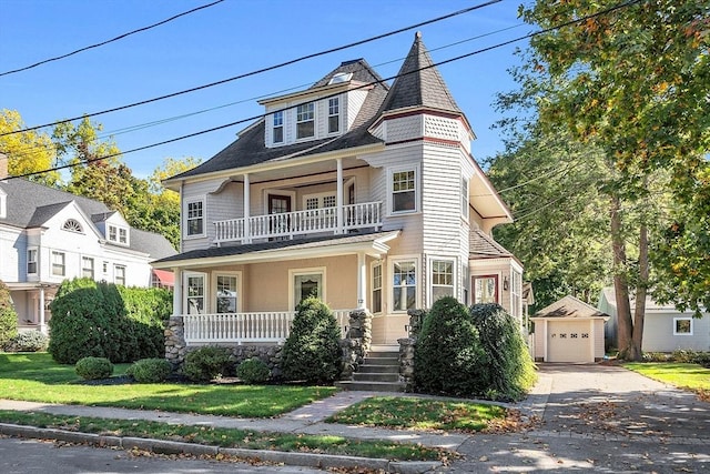 victorian house featuring a balcony, an outbuilding, a garage, and a front lawn