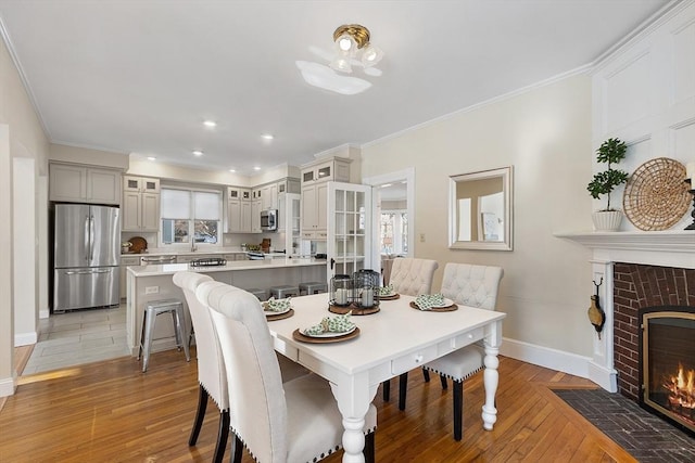 dining room featuring a fireplace, light hardwood / wood-style flooring, a wealth of natural light, and ornamental molding