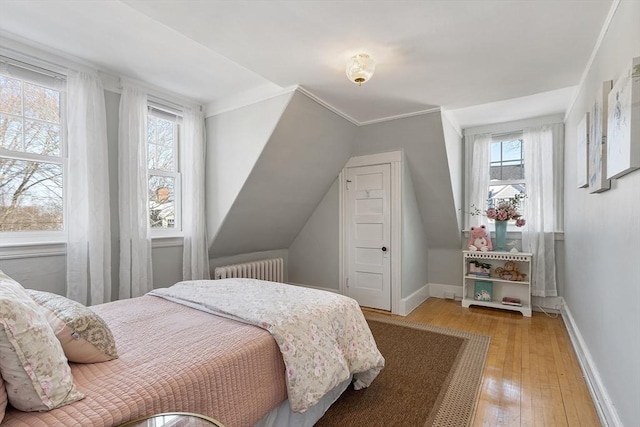 bedroom featuring radiator, crown molding, hardwood / wood-style floors, and multiple windows