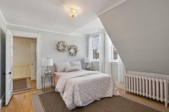 bedroom featuring radiator heating unit, hardwood / wood-style floors, and ornamental molding