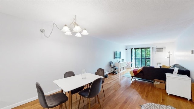 10 Williams St Unit 26, Watertown, MA 02472 - dining space featuring a chandelier, light wood-type flooring, a wall unit AC, a baseboard radiator, and baseboards