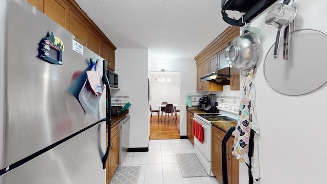 10 Williams St Unit 26, Watertown, MA 02472 - kitchen with stainless steel appliances, backsplash, under cabinet range hood, dark countertops, and brown cabinetry