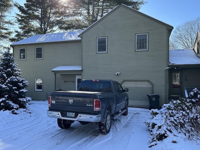 snow covered rear of property featuring a garage