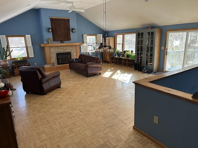 living room featuring a tiled fireplace, vaulted ceiling, parquet flooring, and ceiling fan