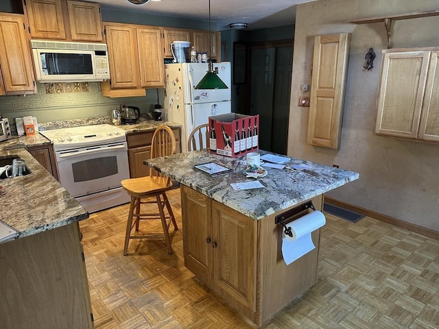 kitchen with white appliances, light stone countertops, a center island, and light parquet floors