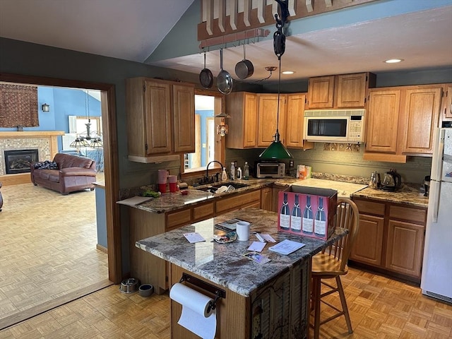 kitchen with sink, a breakfast bar area, white appliances, light parquet flooring, and light stone countertops