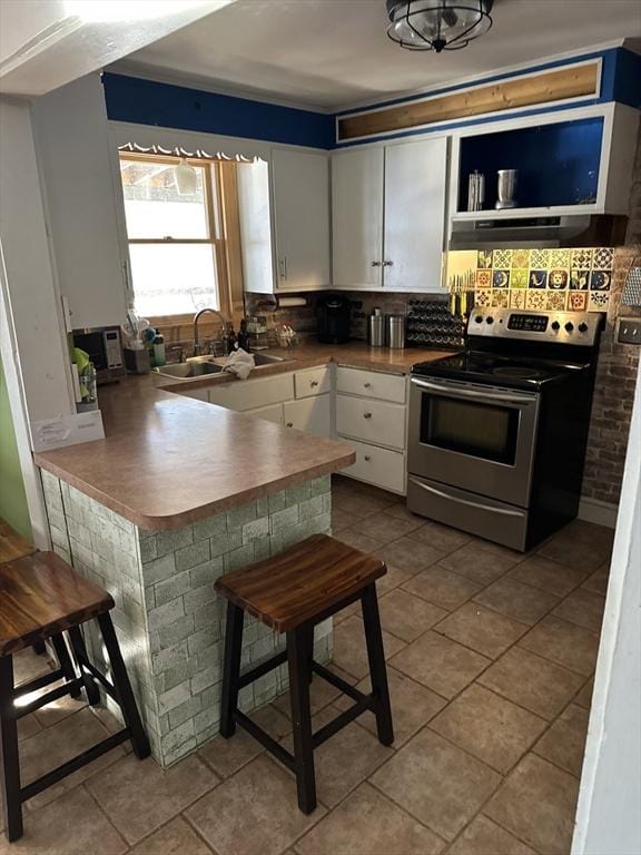 kitchen with light tile patterned flooring, sink, white cabinetry, electric range, and kitchen peninsula