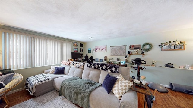 living room with a textured ceiling, light wood finished floors, and baseboards