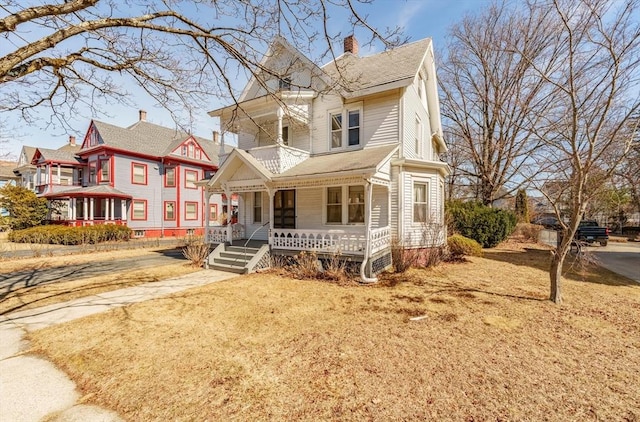 victorian house featuring a porch and a chimney